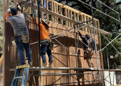 concrete wall forming, three workers putting up wood and rebar to setup a retaining wall.